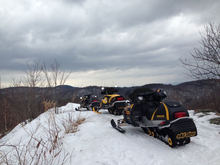 Parked snowmobiles on a trail with view of the mountains Parked snowmobiles on a trail with view of the mountains